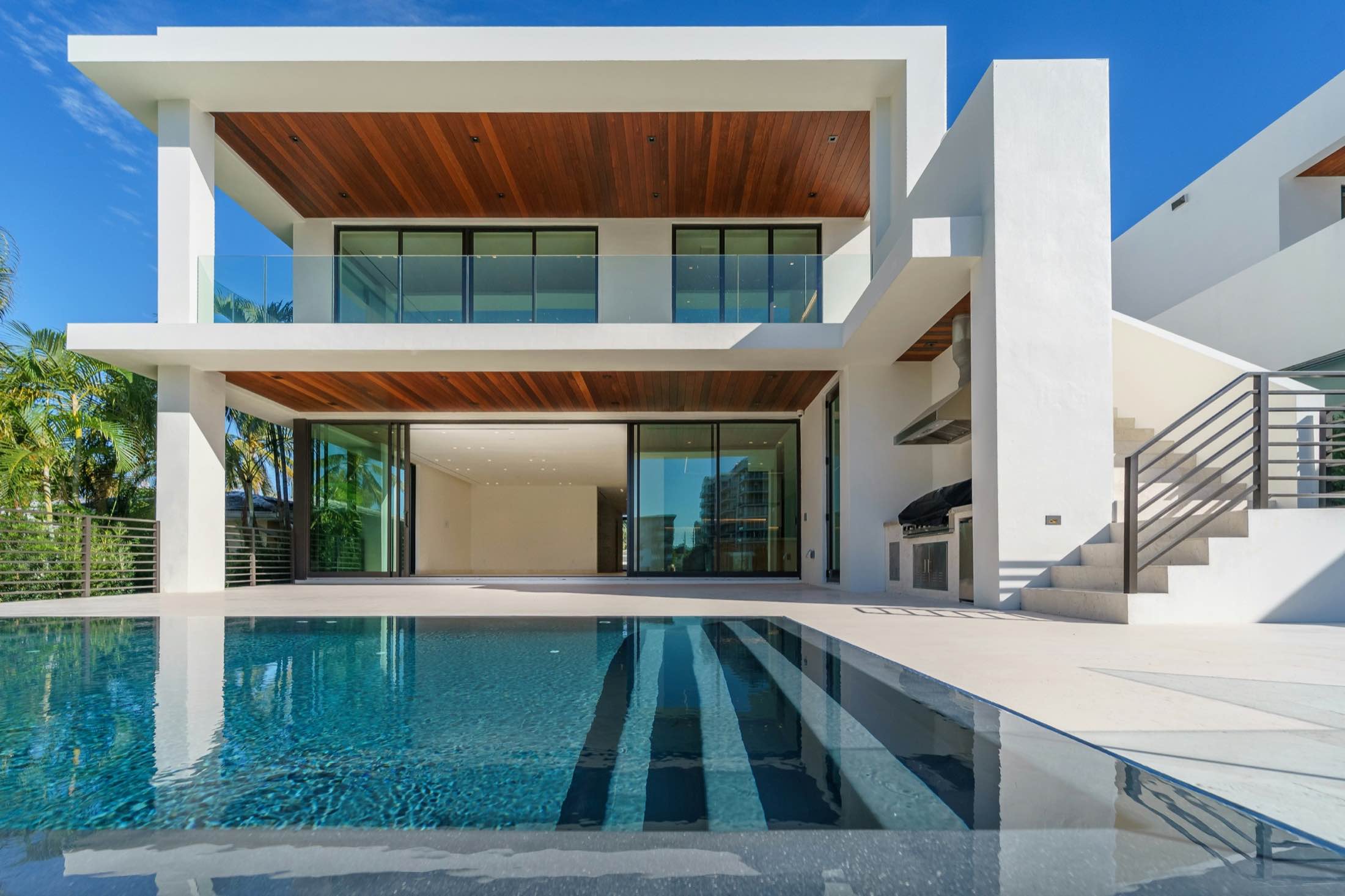 A white modern home with a cantilevered upper floor over a reflecting pool