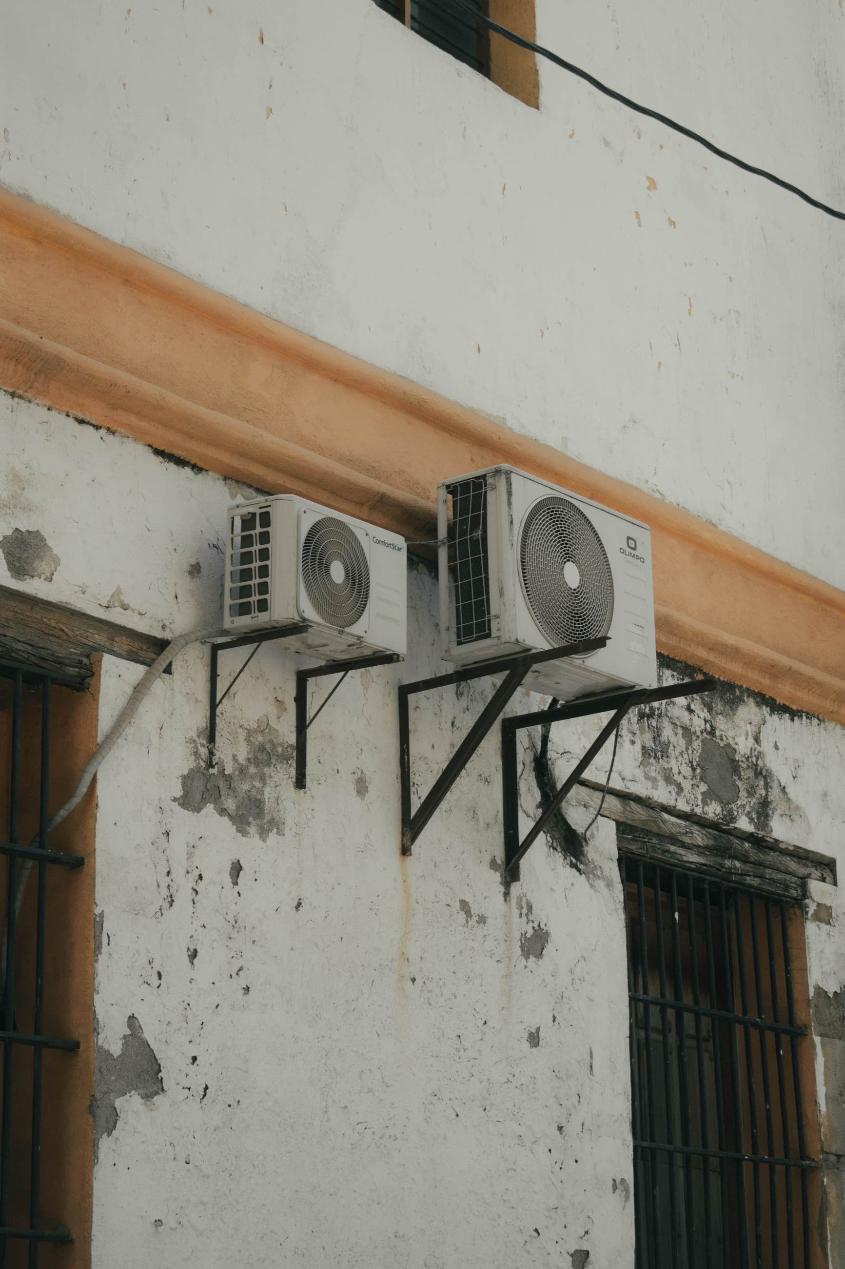 Two outdoor heat-pump units mounted on brackets beneath a timber beam